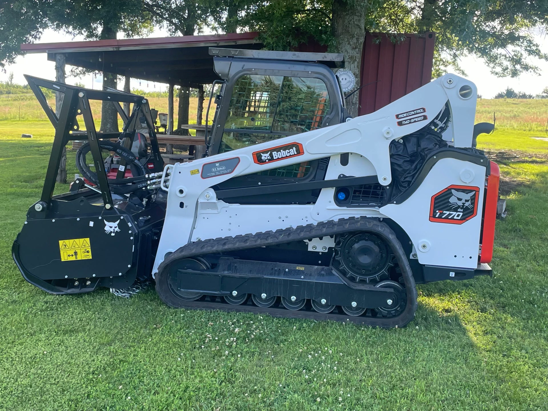 Bobcat T770 compact track loader with a forestry mulcher attachment parked on grass