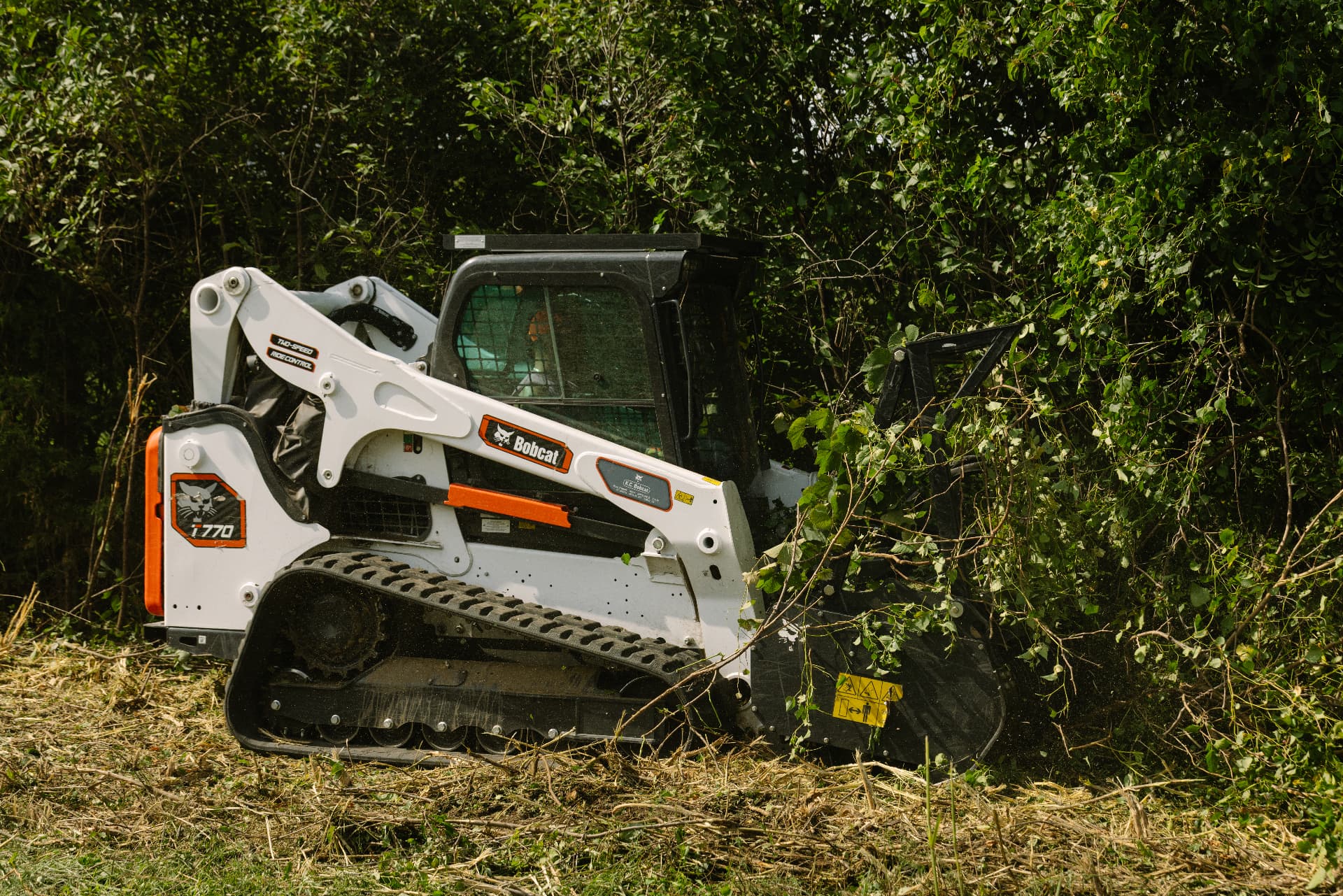 Bobcat T770 compact track skid steer pushing into dense brush and overgrowth