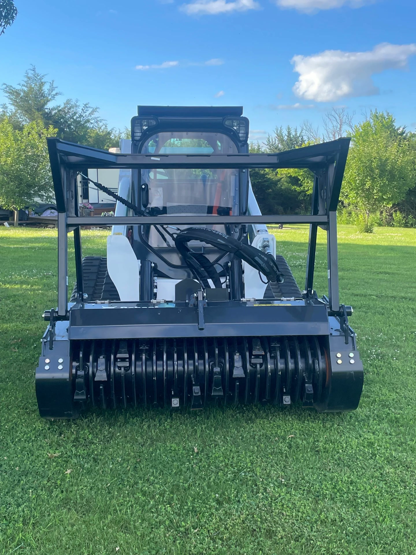 Front view of the forestry mulcher drum attachment on the skid steer